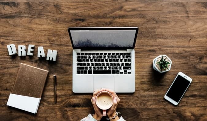 a laptop on a desk with coffee and a notebook