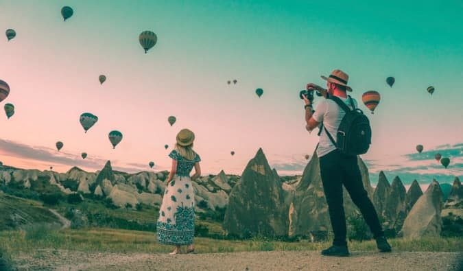 a couple taking photos of hot air balloons