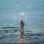 A man holding a sparkler while under water